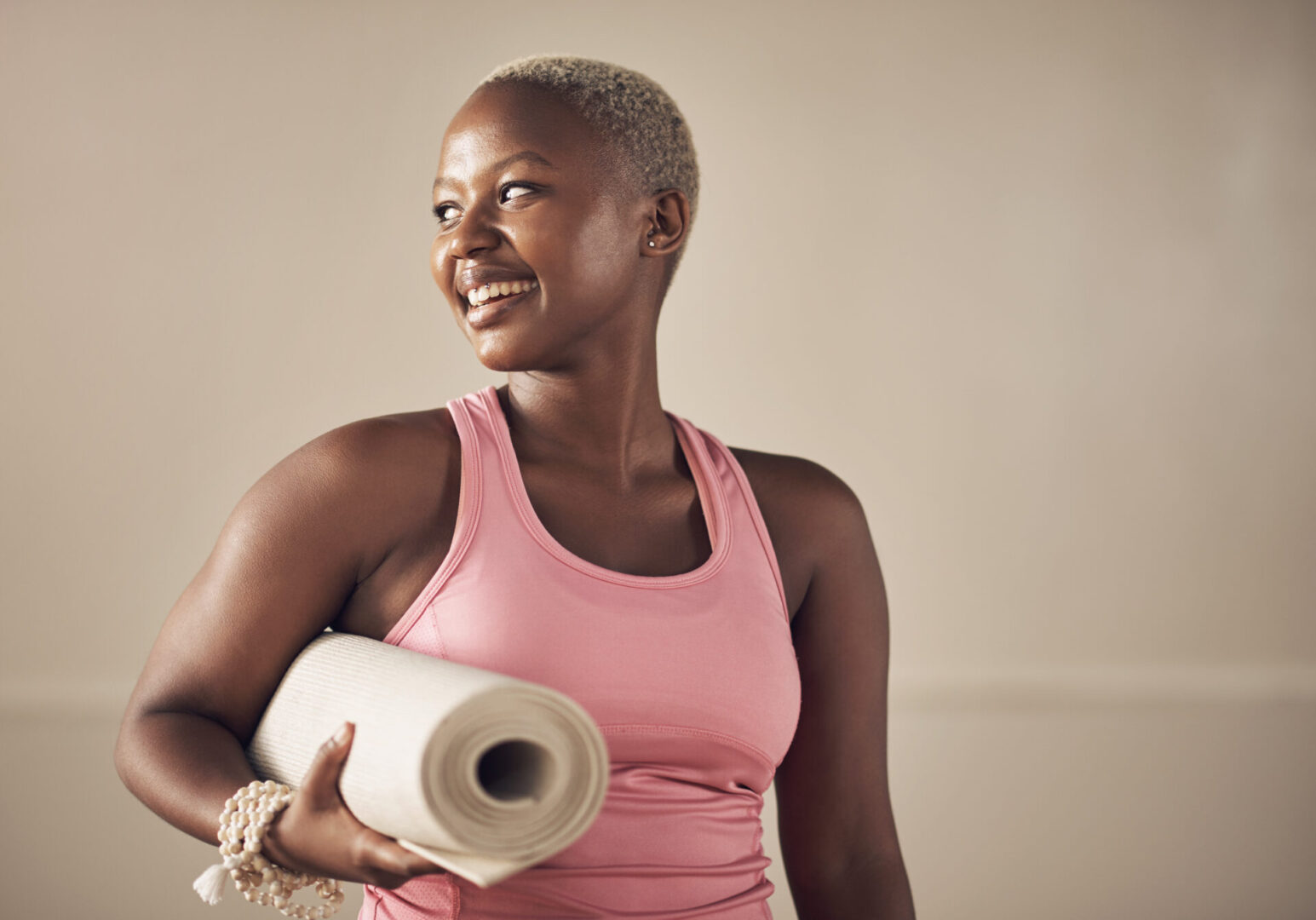 Cropped shot of an attractive young woman standing alone and holding her yoga mat before an indoor yoga session