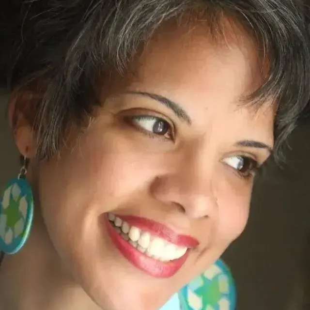 A woman with big earrings smiles for the camera.