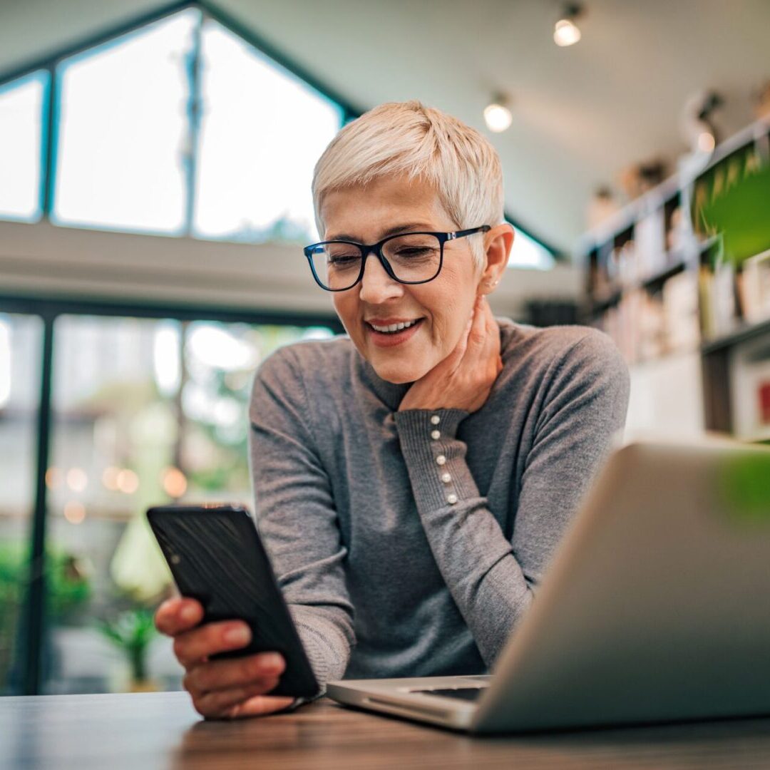 A woman sitting at a table looking at her phone.